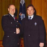 Detective Sergeant John Gilbert (right) received an award for long service with the Metropolitan Police from Commissioner Sir John Stevens in 2002.