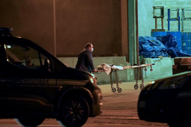 A man wheels a gurney into a warehouse in the Port of Calais, France, where it is believed the bodies of migrants are being transported after recovery from a boat which capsized off the French coast with the loss of 31 lives